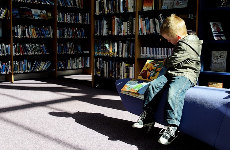 صورة طفل فى المكتبة يقرأ